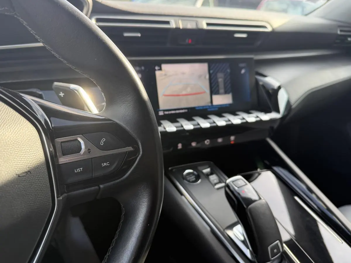 Vue intérieure centrée sur le volant cuir et la console centrale avec écran tactile et commandes chromées Peugeot 508 bleu.