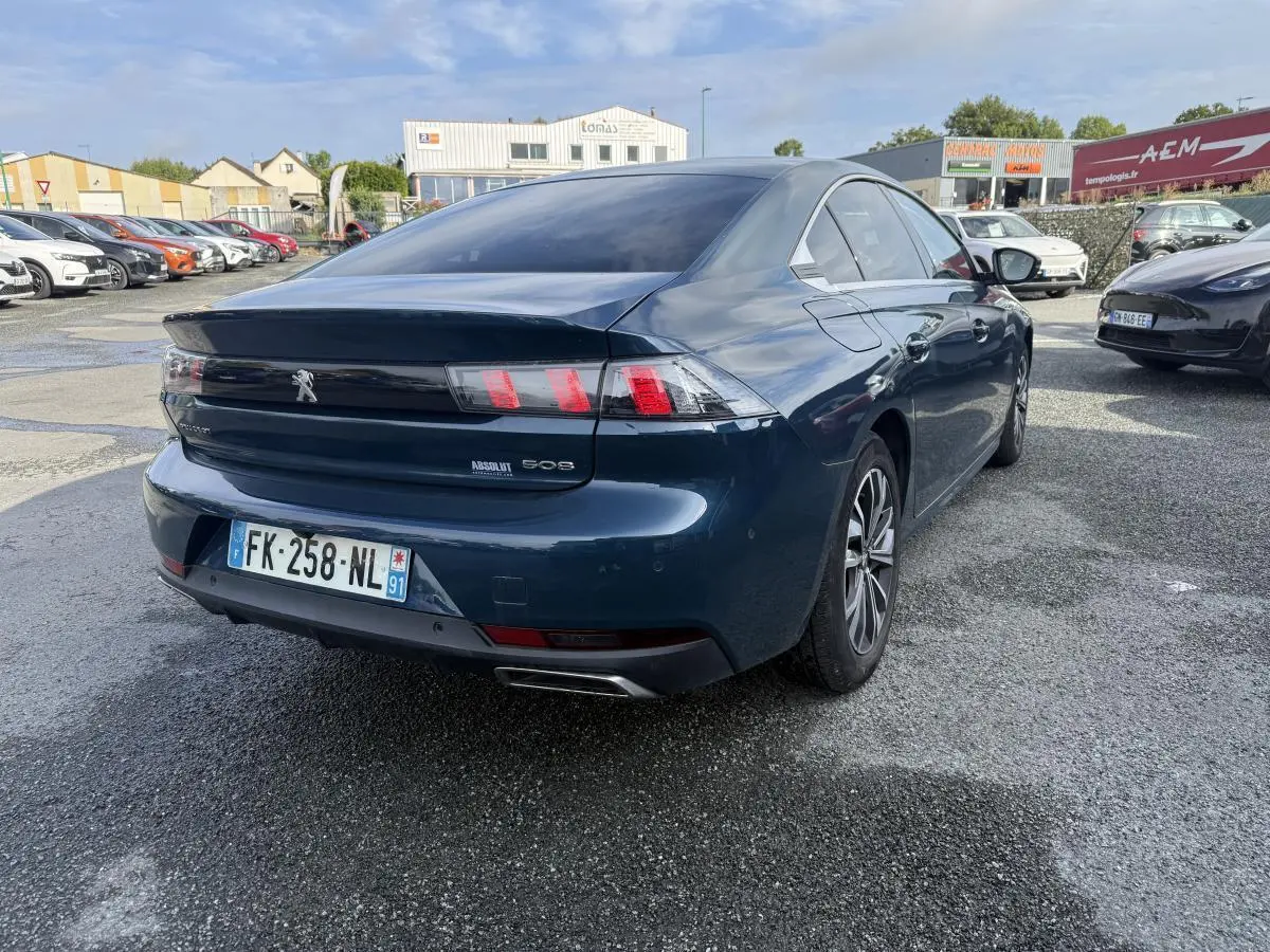 Vue 3/4 arrière droite d'une Peugeot 508 bleu métallisé avec feux arrière LED et double sortie d'échappement chromée.