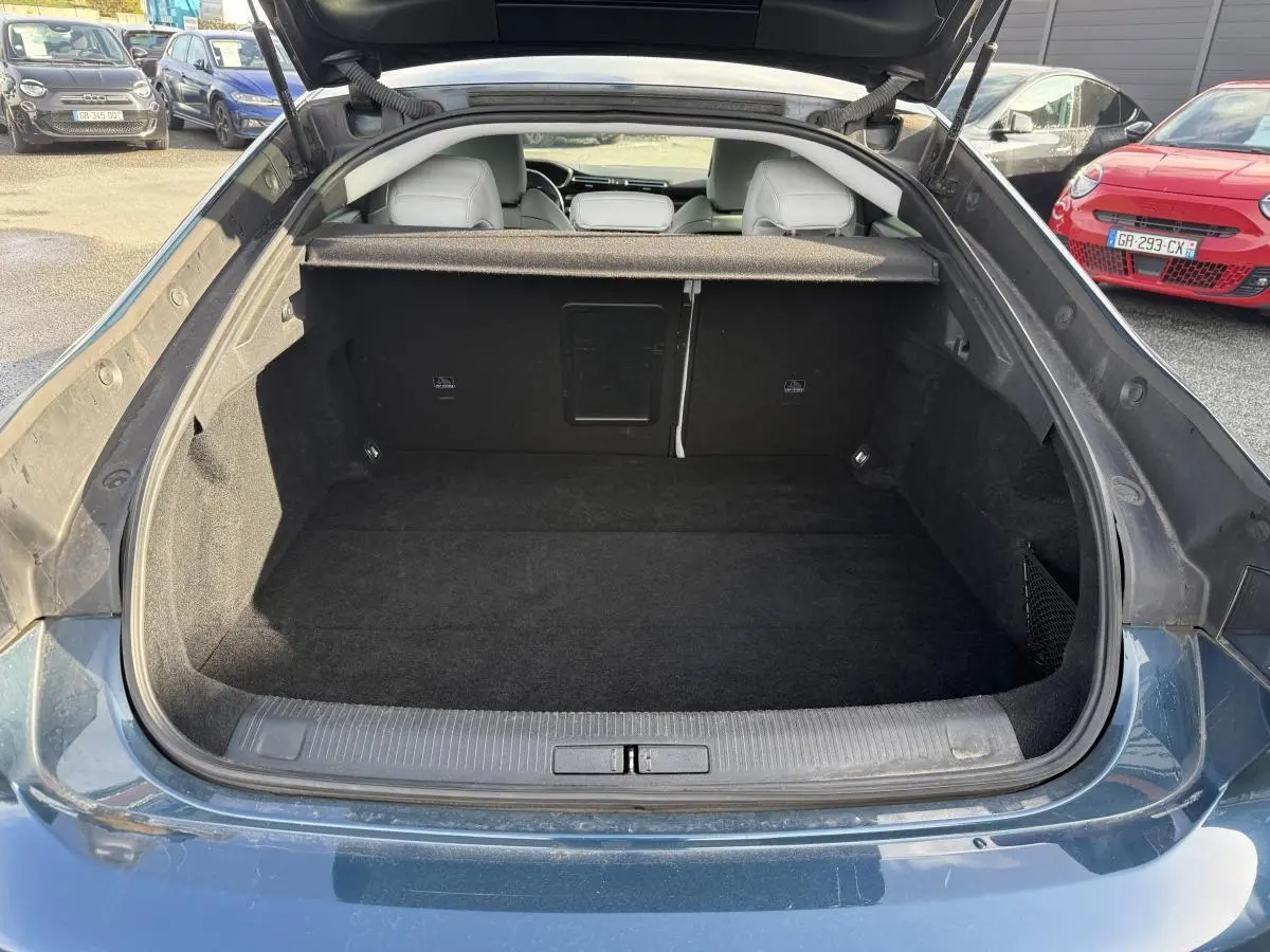 Coffre ouvert vu de l'arrière d'une Peugeot 508 bleu métallisé, montrant un espace de chargement propre et vide.
