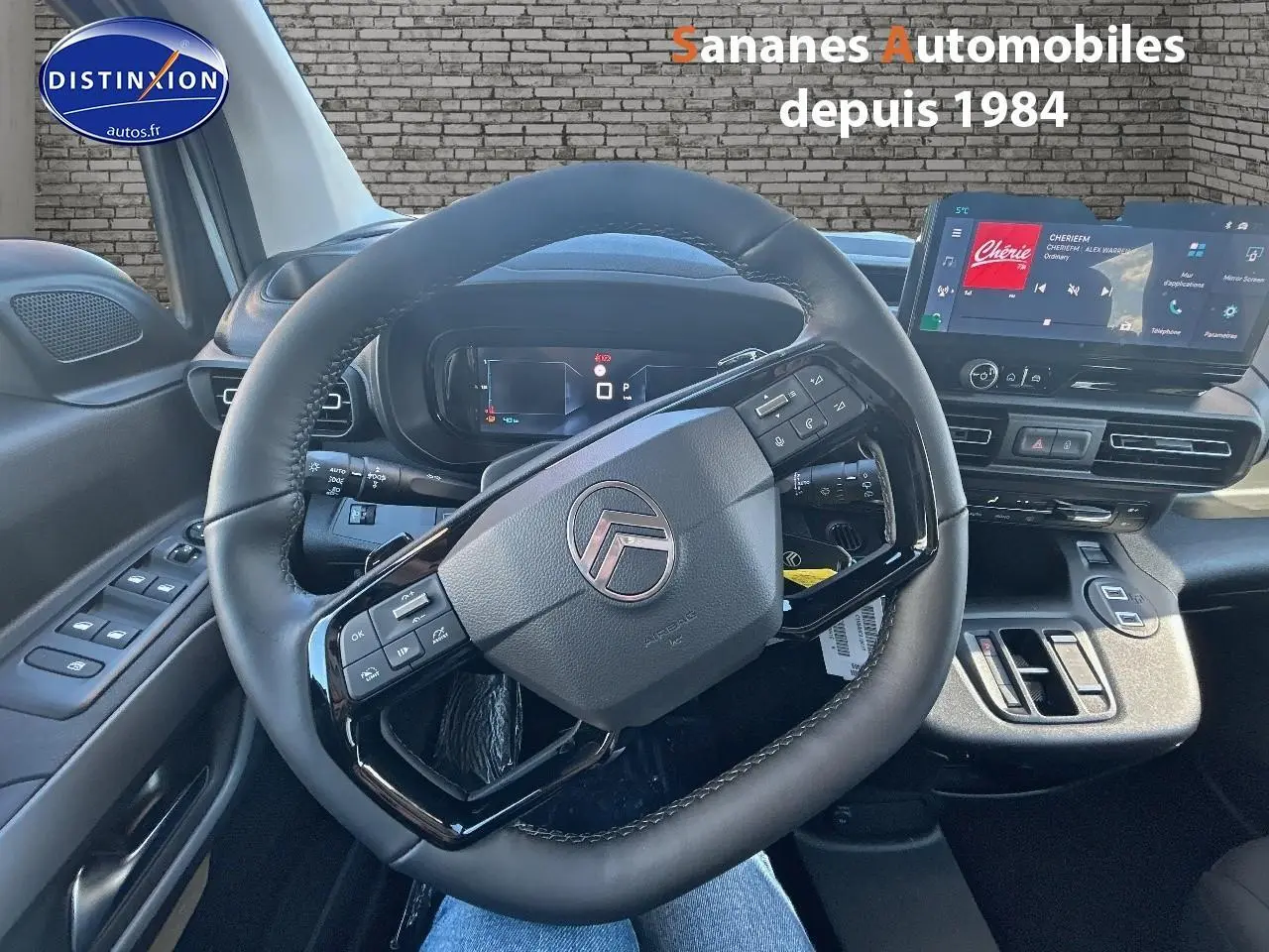 Vue intérieure centrée sur le volant cuir noir et le tableau de bord numérique du Citroën Berlingo blanc 2025.