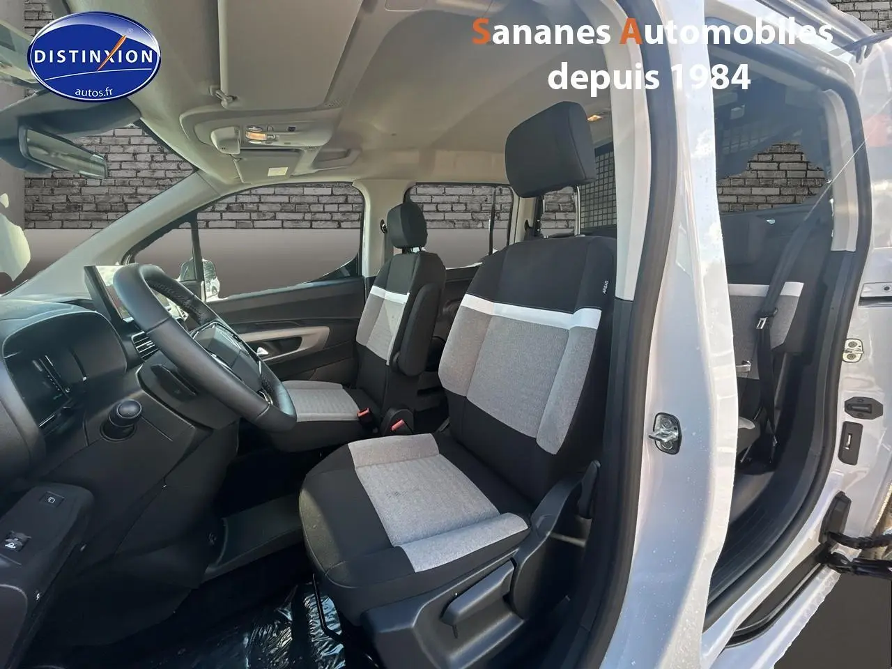 Vue intérieure côté gauche du Citroën Berlingo blanc 2025 montrant les sièges avant gris et noirs et le tableau de bord.