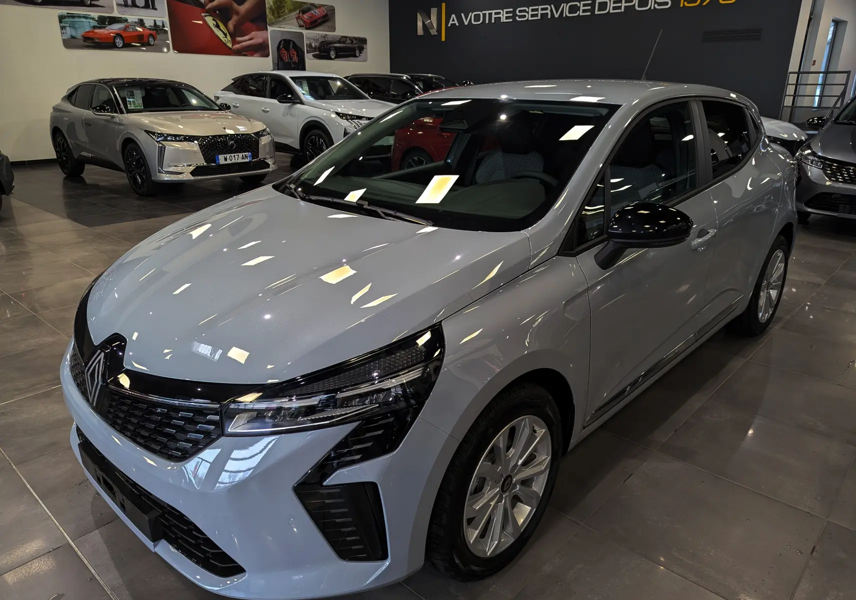 Renault Clio V Blue dCi 100 en gris Rafale, vue 3/4 avant droit, avec calandre noire et jantes argentées.