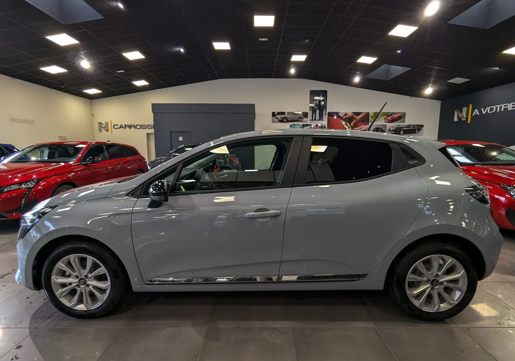Renault Clio V gris Rafale vue de profil côté gauche, en intérieur avec jantes alliage et vitres teintées.