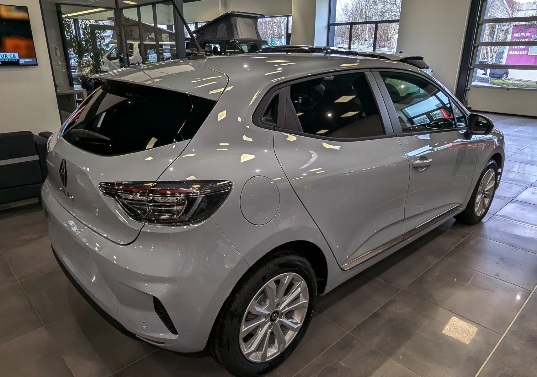 Vue 3/4 arrière droit d'une Renault Clio V gris Rafale en showroom, avec vitres teintées et jantes alliage.