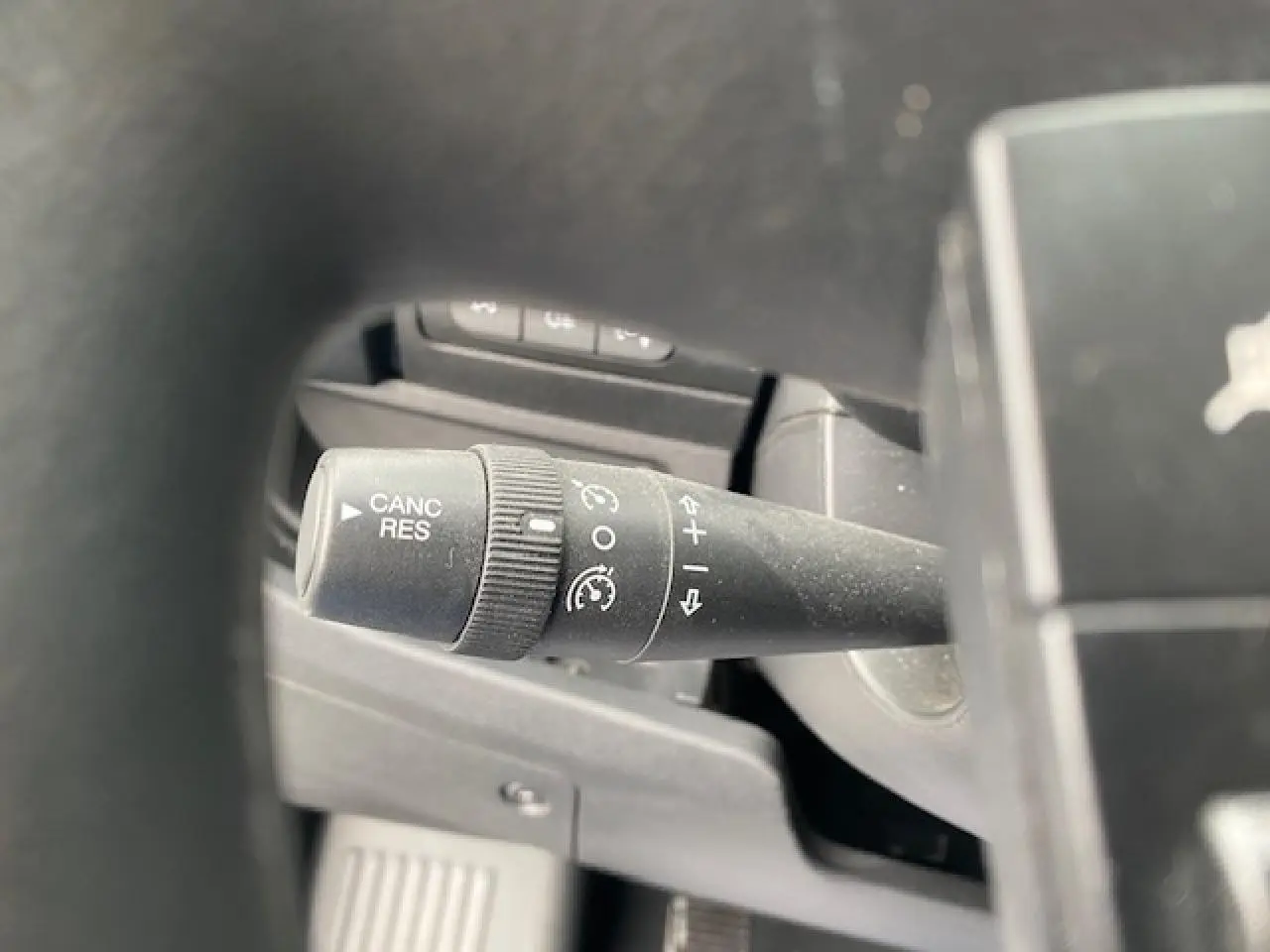 Gros plan sur la commande de régulateur de vitesse à gauche du volant dans l’habitacle du fourgon Opel Movano blanc.
