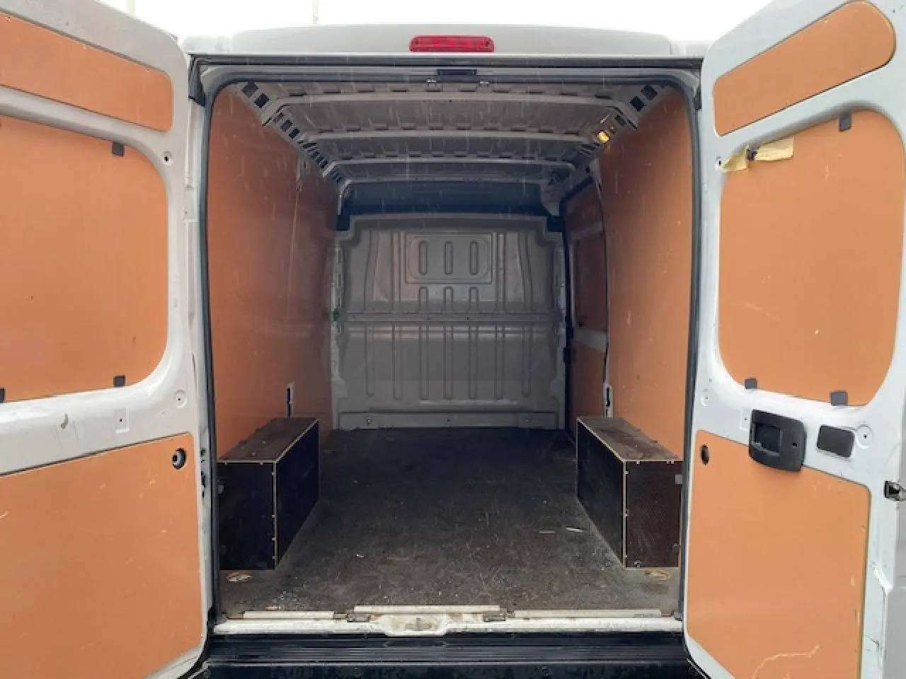 Vue arrière intérieure du fourgon blanc Opel Movano 2023 avec plancher bois et parois orange.
