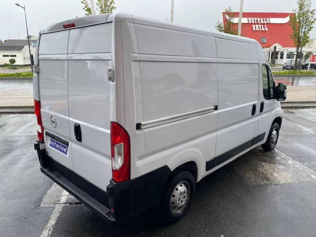 Vue 3/4 arrière droite d’un Opel Movano Fourgon blanc avec porte latérale coulissante et hayon arrière fermé.