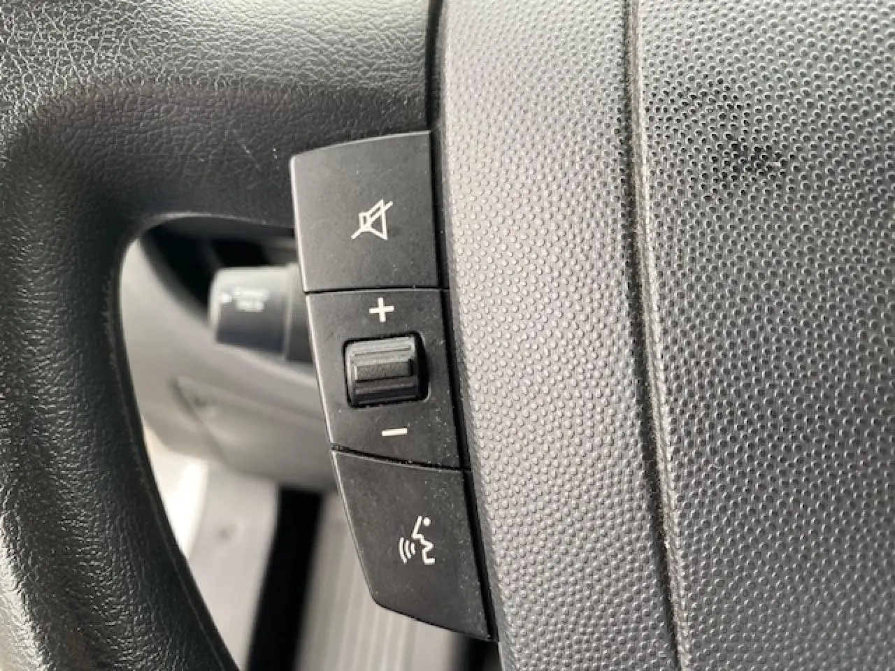 Gros plan sur les commandes de volume et de coupure du son au volant du fourgon blanc Opel Movano 2023.