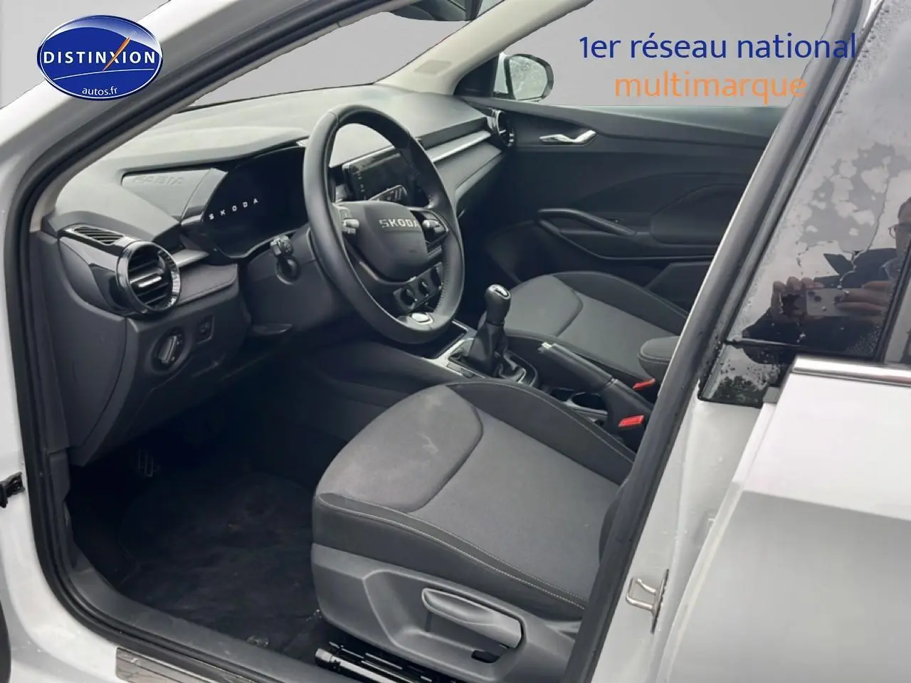 Intérieur de la Skoda Fabia blanc vue côté conducteur, montrant sièges noirs et tableau de bord moderne.