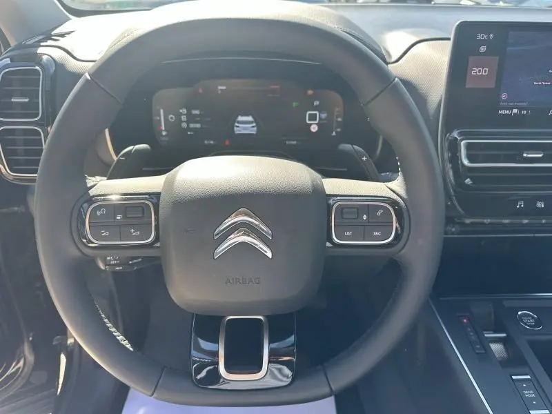 Vue rapprochée du volant noir du Citroën C5 Aircross 2025 avec commandes intégrées et tableau de bord numérique.