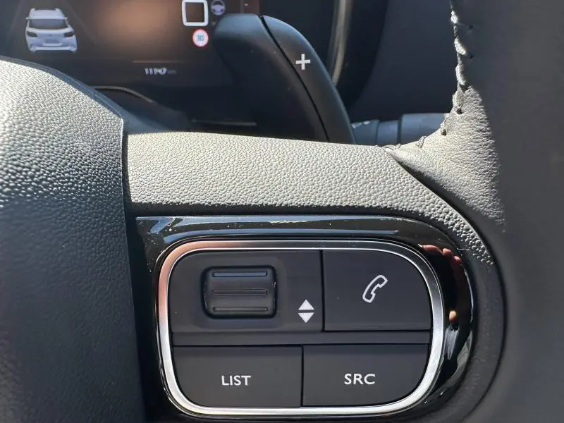 Gros plan sur les commandes du volant côté droit du Citroën C5 Aircross noir Perla Nera avec palettes au volant visibles.