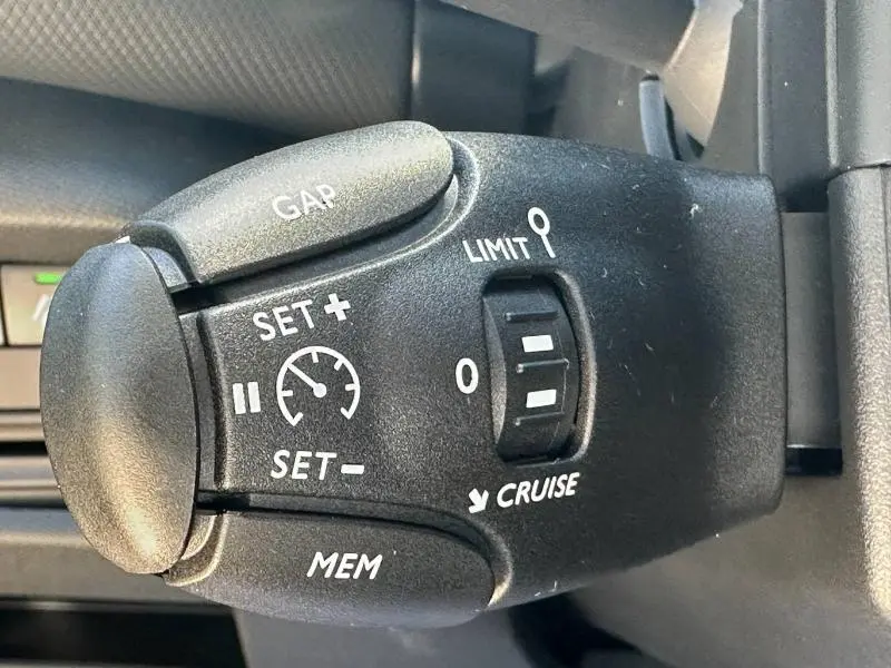 Gros plan sur la commande de régulateur de vitesse du Citroën C5 Aircross 2025 en plastique noir avec marquages blancs.