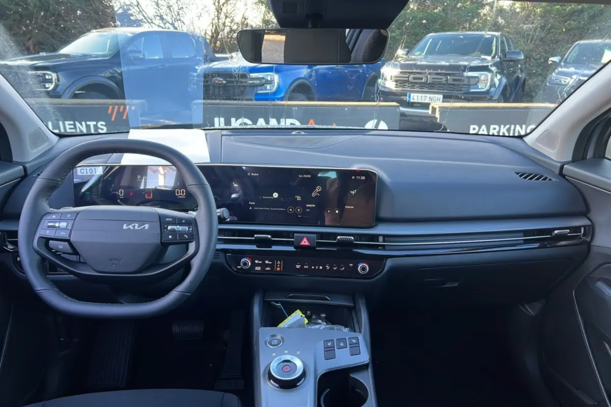 Vue intérieure avant du Kia Sportage 1.6 T-GDI HEV 239 EX 2026, tableau de bord moderne avec écran large et volant multifonctions.