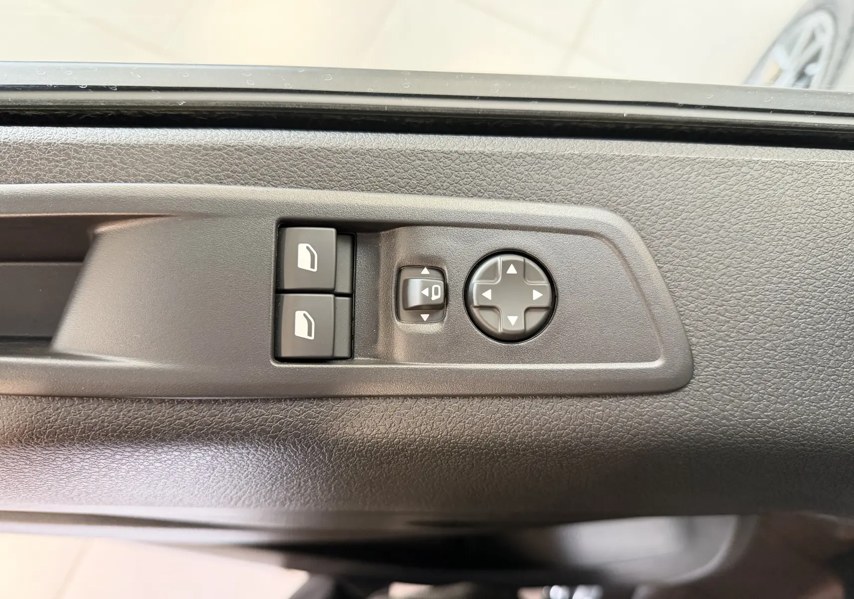 Détail des commandes de réglage des rétroviseurs sur la porte côté conducteur d'un Citroën Jumpy gris titane.