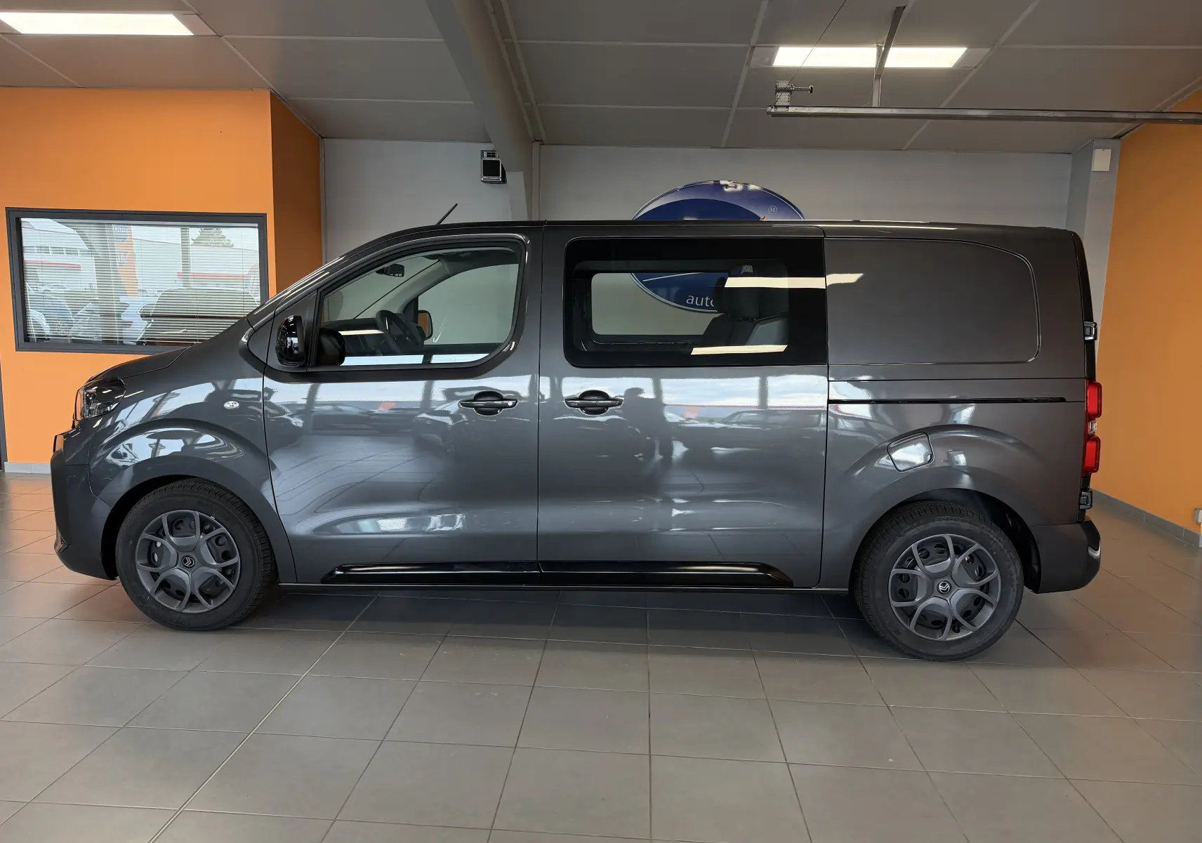 Vue de profil côté gauche d'un Citroën Jumpy Cabine Approfondie gris titane avec porte coulissante et jantes noires 17 pouces.