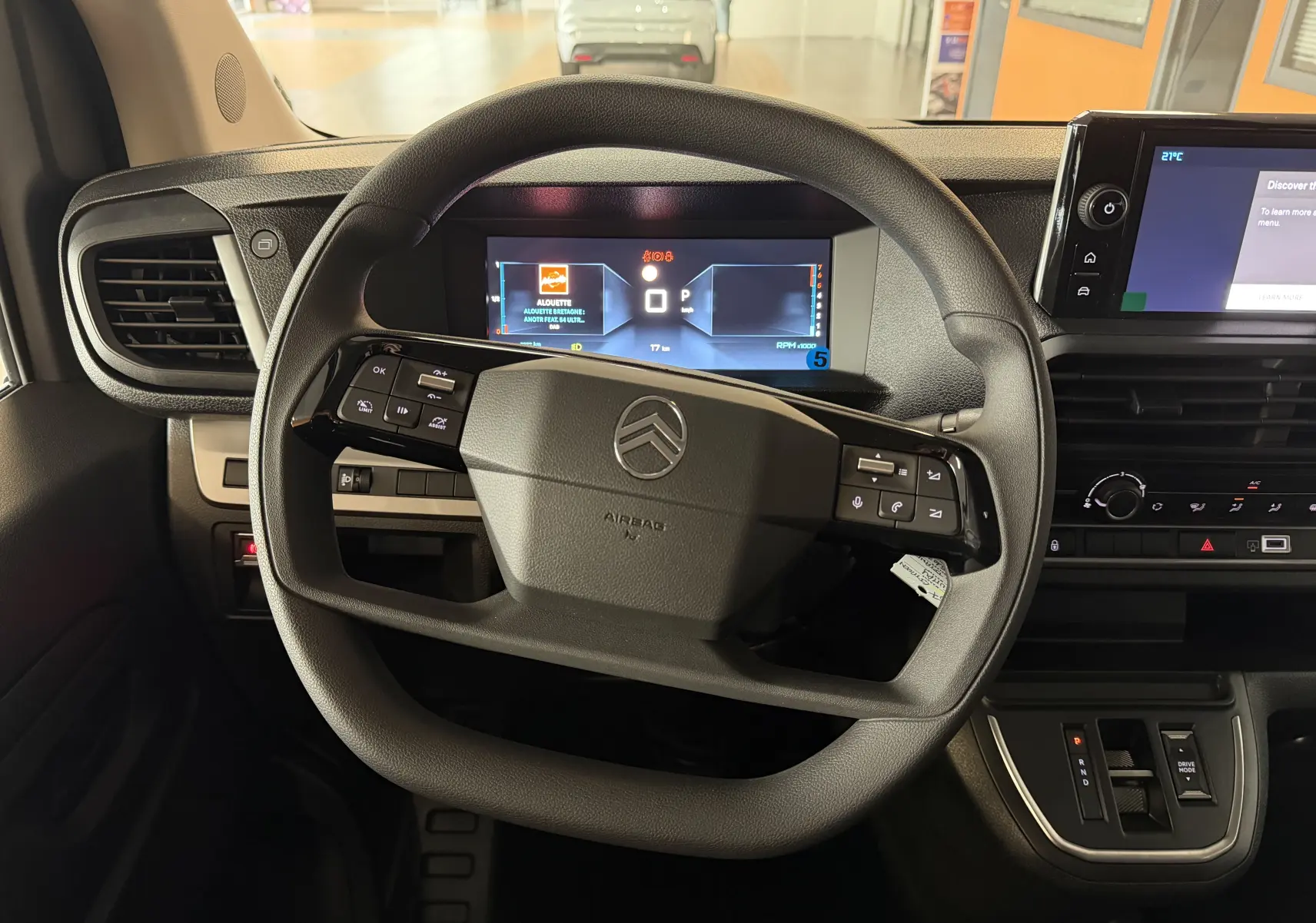 Vue intérieure centrée sur le volant multifonction noir et le combiné numérique du Citroën Jumpy Cabine Approfondie gris titane.