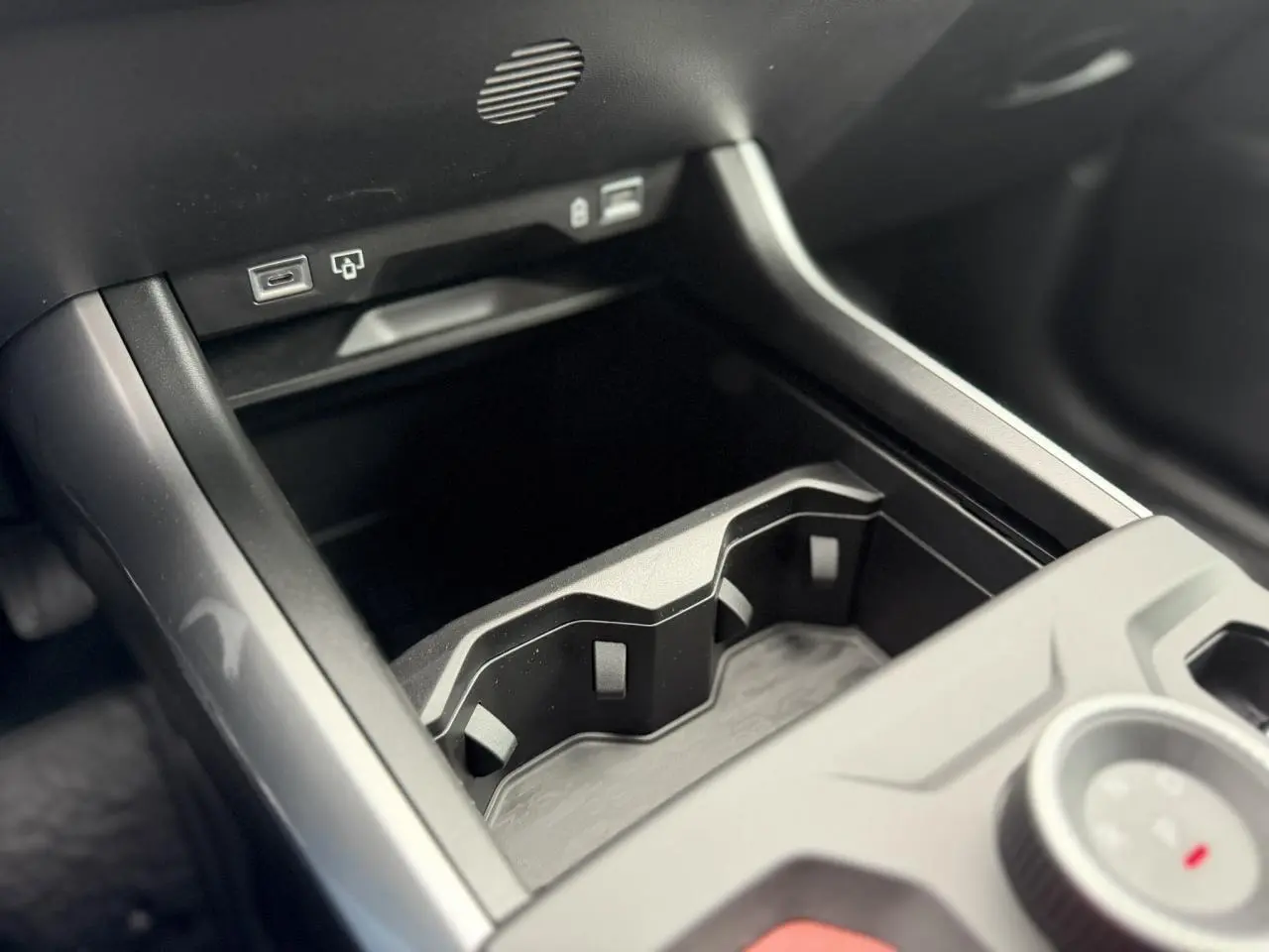 Gros plan sur la console centrale noire du Jeep Compass Hybrid 2026, avec porte-gobelets et ports USB visibles.