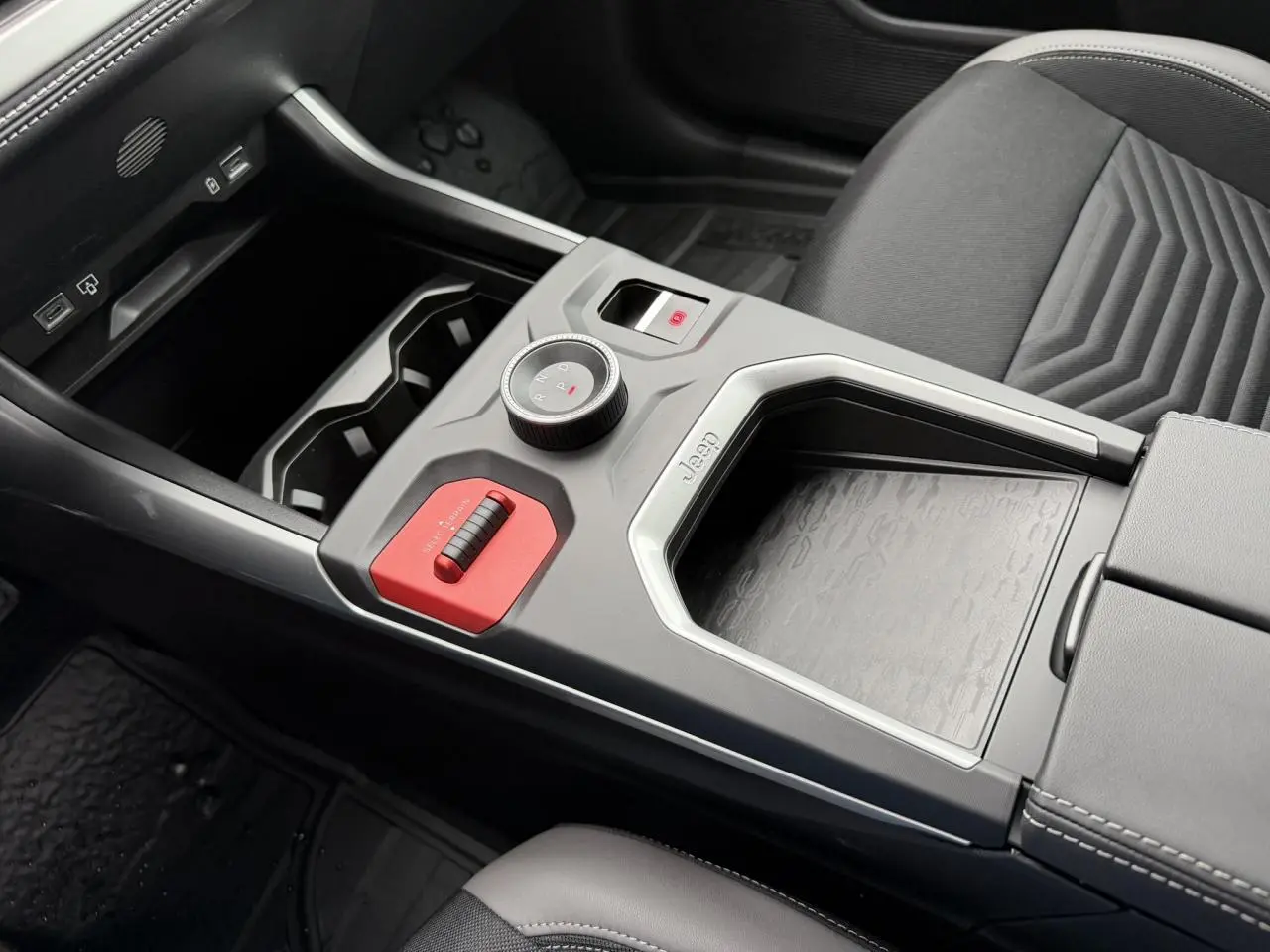 Vue rapprochée de la console centrale noire du Jeep Compass Hybrid 2026 avec molette de sélection et insert rouge distinctif.