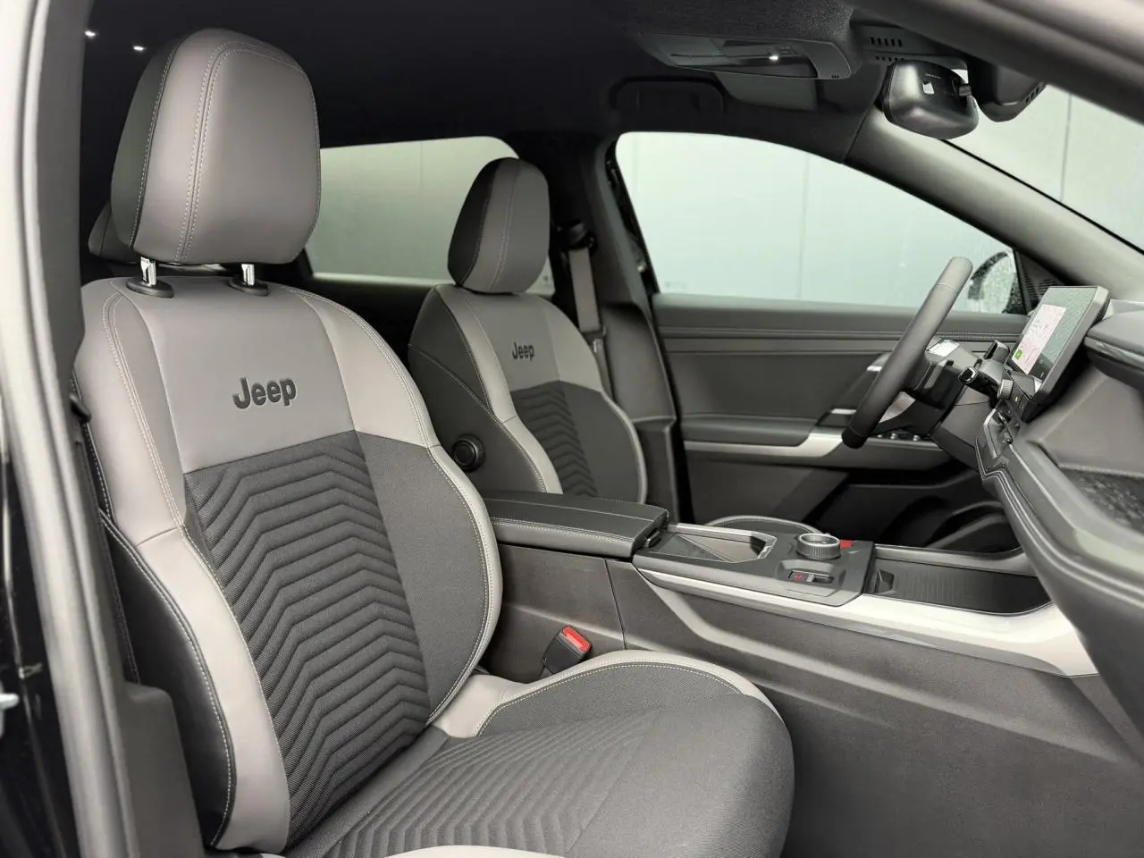 Vue intérieure côté droit du Jeep Compass 2026, sièges gris avec logo Jeep et console centrale moderne.