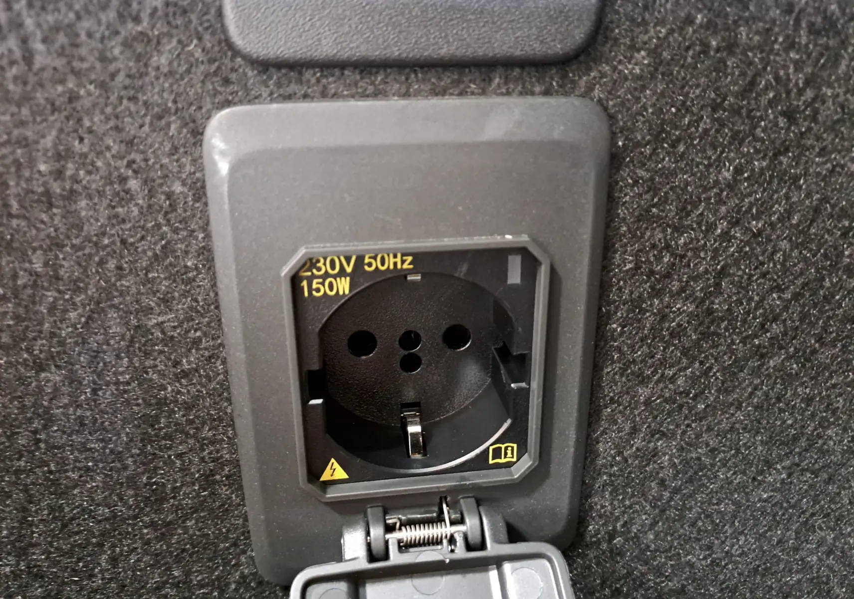 Prise électrique 230V 150W intégrée dans le coffre du CUPRA LEON ST 1.5 eTSI 2025, finition Noir Minuit.