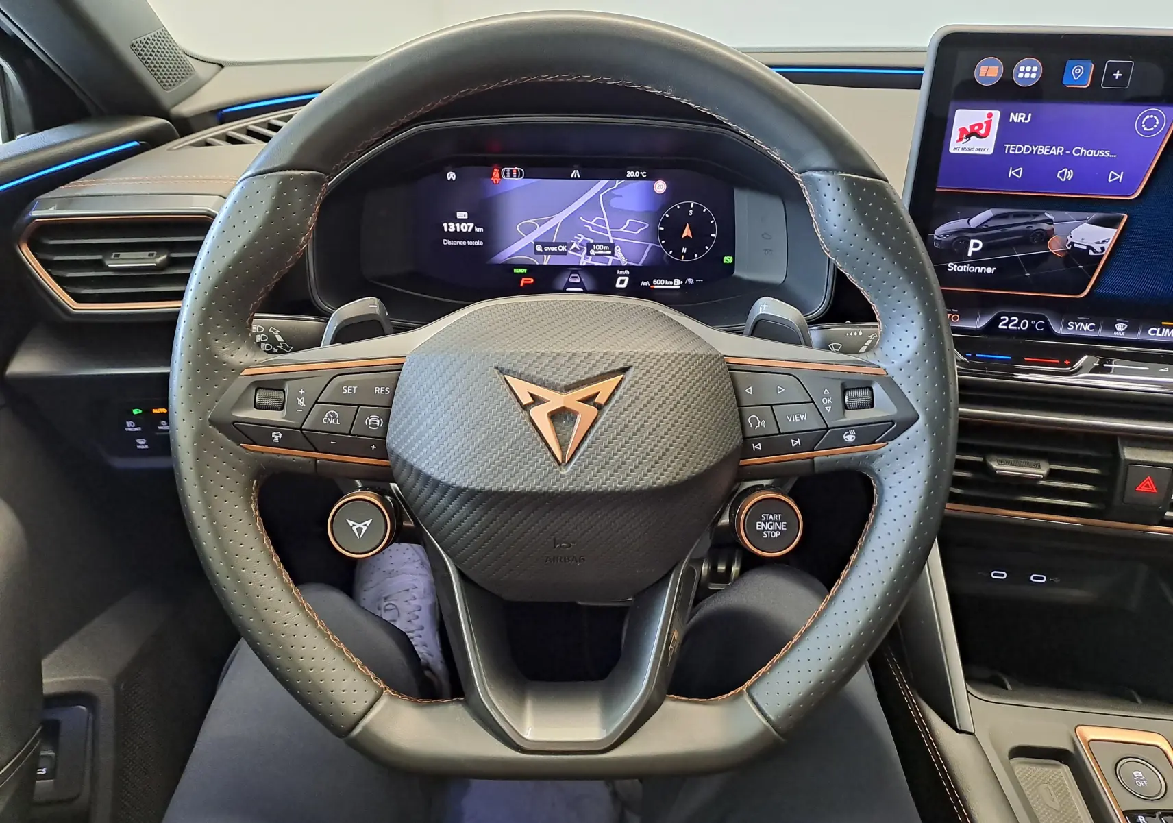 Vue intérieure centrée sur le volant perforé avec logo Cupra cuivré et tableau de bord numérique du Leon ST 2025.