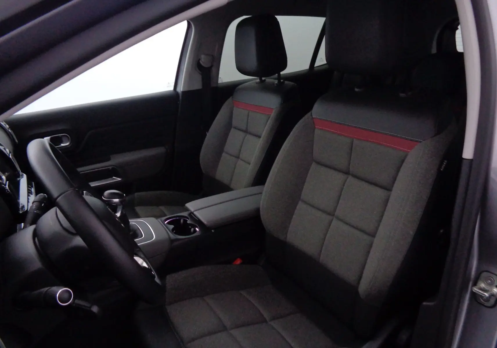 Vue intérieure côté conducteur du Citroën C5 Aircross 2021, sièges gris avec surpiqûres rouges et volant noir.