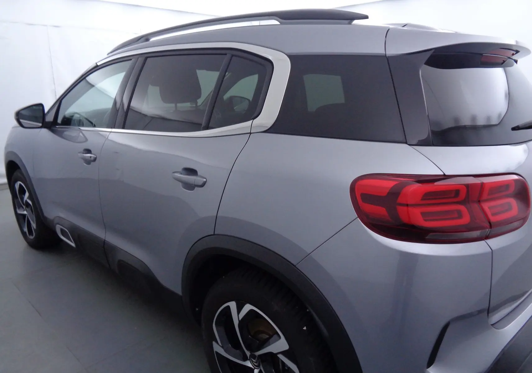 Vue 3/4 arrière droit d'un Citroën C5 Aircross gris Artense métallisé avec toit noir et feux arrière LED distinctifs.