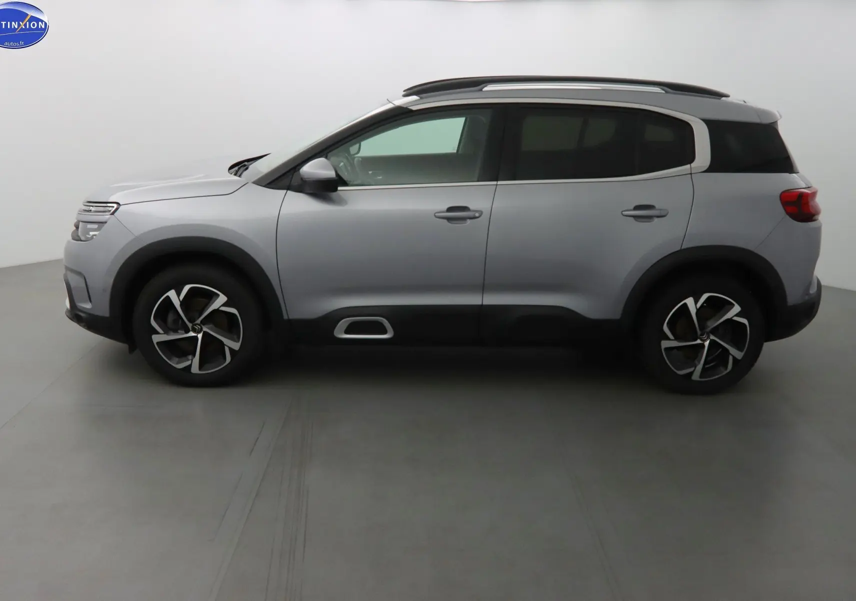 Profil côté gauche d'un Citroën C5 Aircross gris Artense métallisé avec jantes bi-ton et barres de toit.