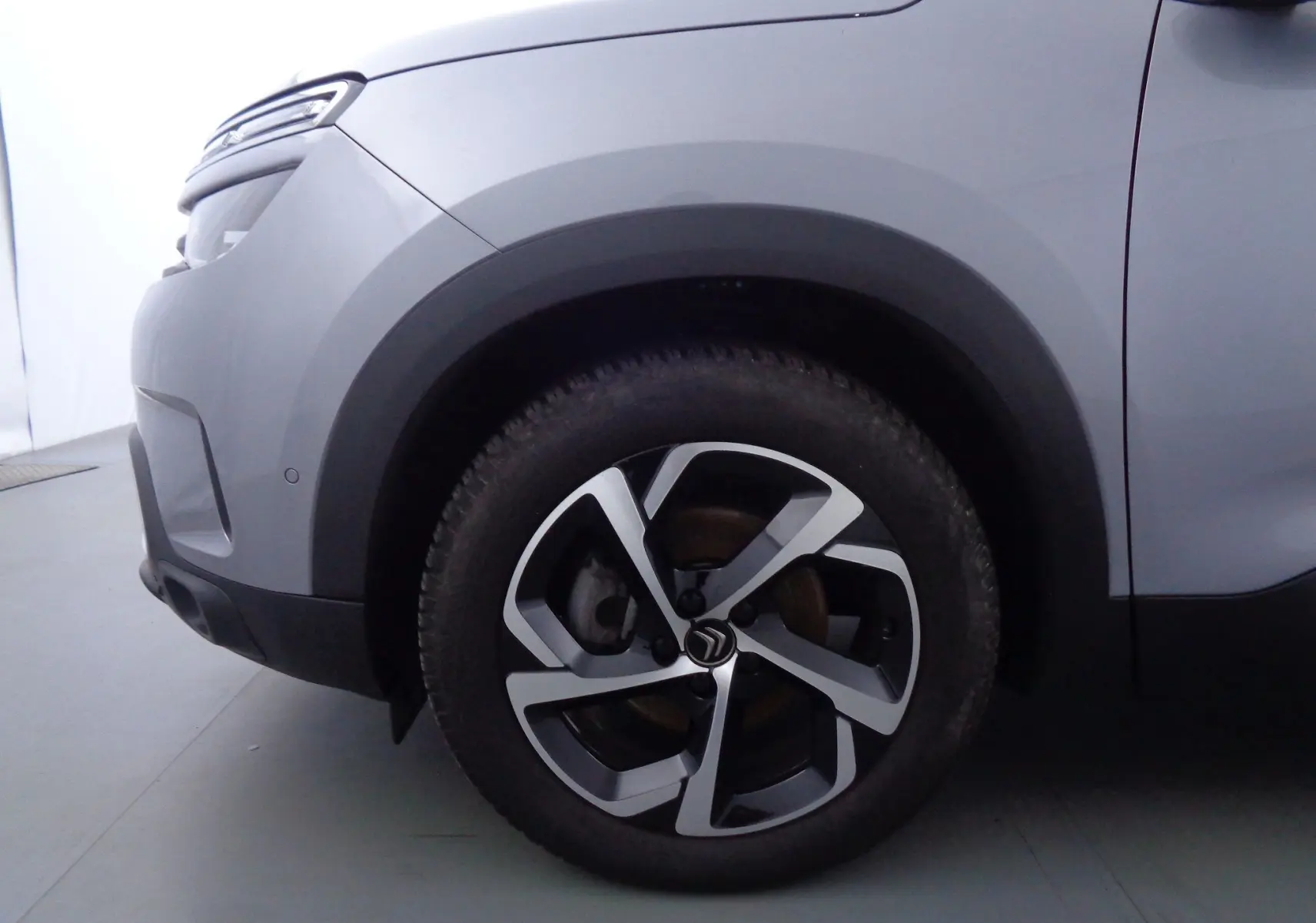 Gros plan sur la roue avant gauche d'un Citroën C5 Aircross gris Artense métal avec jante alliage bicolore.