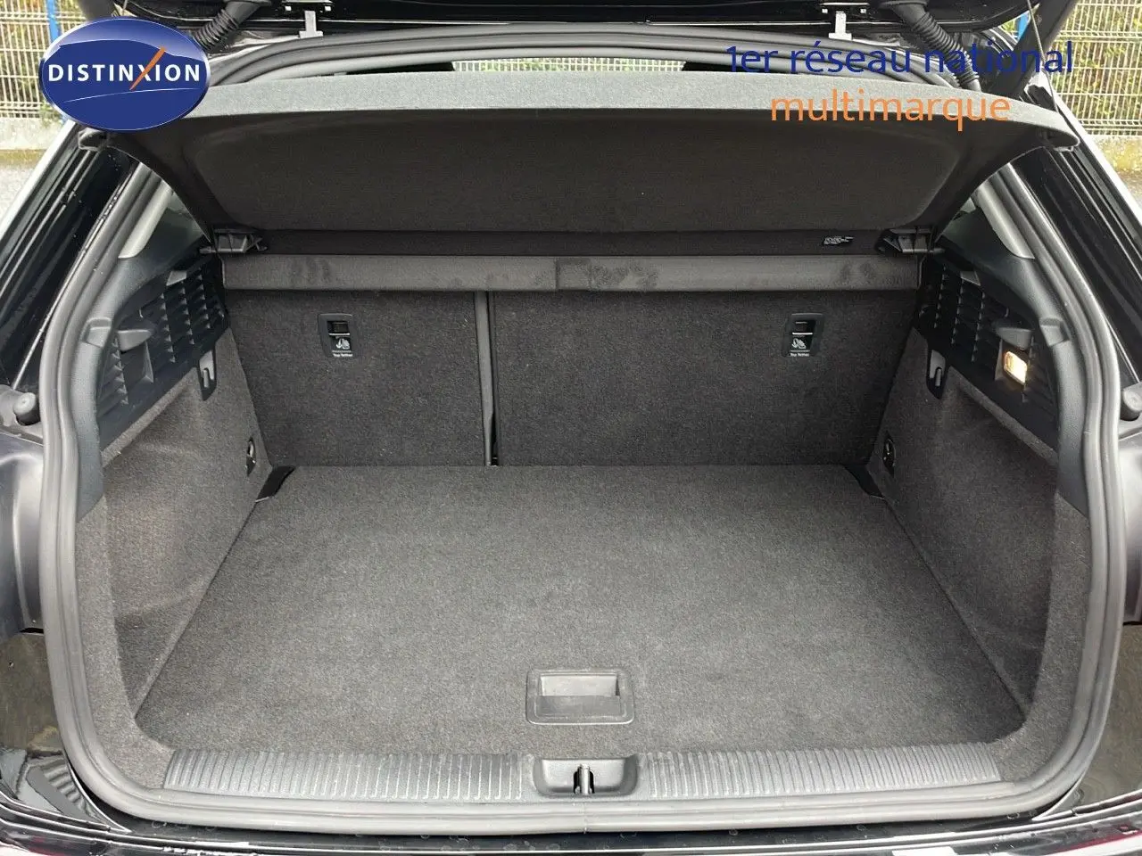 Coffre ouvert vu de l'arrière d'un Audi Q2 noir Mito Metal, montrant un espace de chargement propre et spacieux.