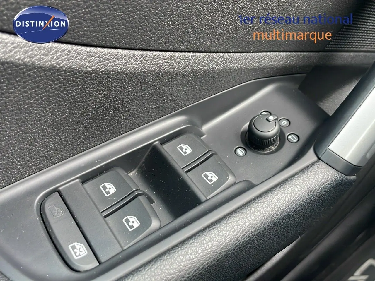 Gros plan sur les commandes des vitres électriques et réglages des rétroviseurs côté conducteur d'un Audi Q2 noir Mito Metal.