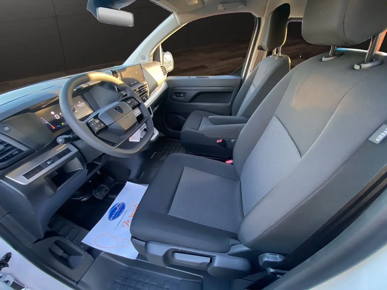 Vue intérieure côté conducteur du Peugeot Expert cabine approfondie 2025, sièges tissu bi-ton gris et noir.