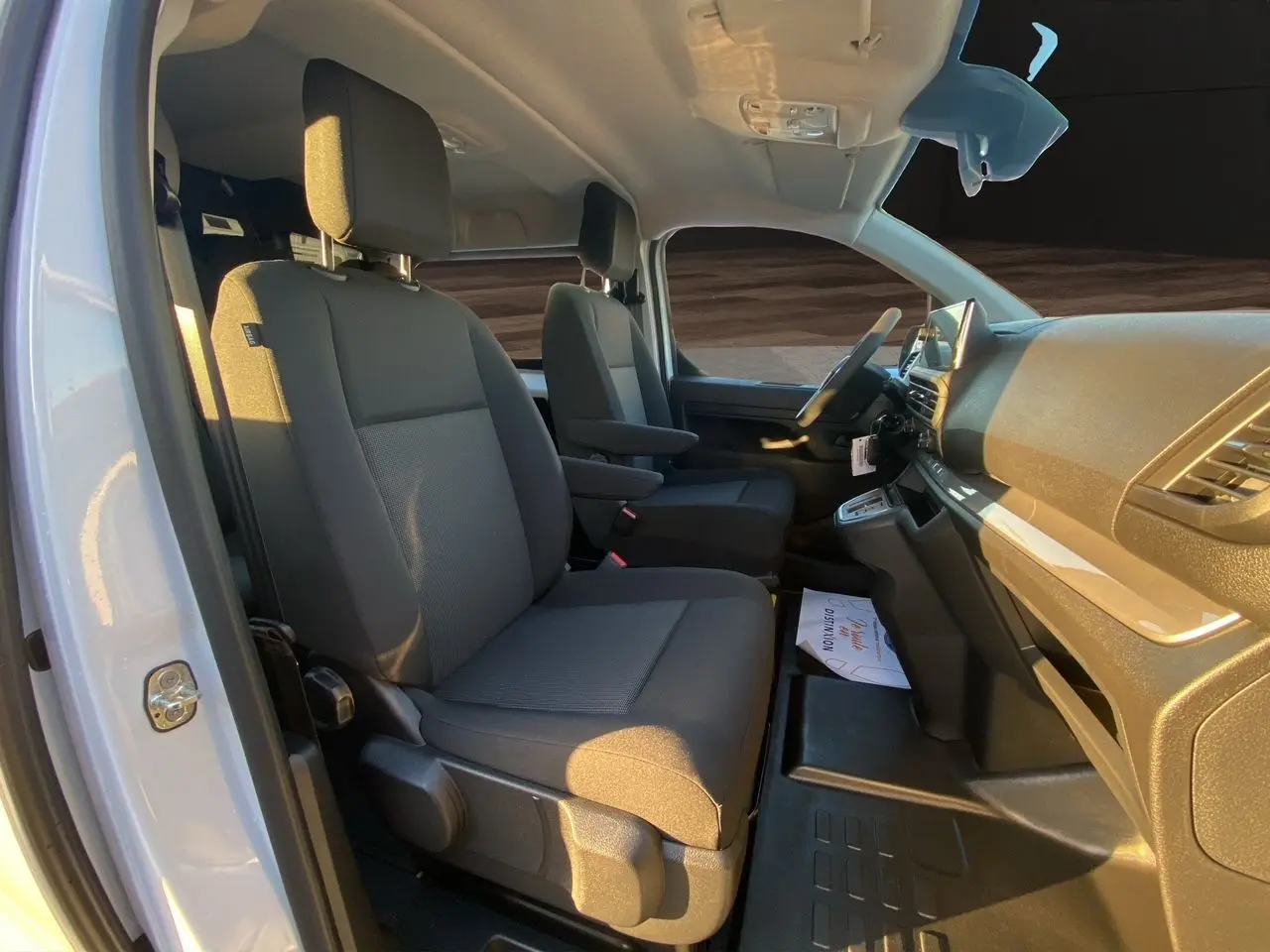 Vue intérieure côté conducteur du Peugeot Expert cabine approfondie blanc Icy, sièges tissu gris avec accoudoirs et tableau de bord moderne.