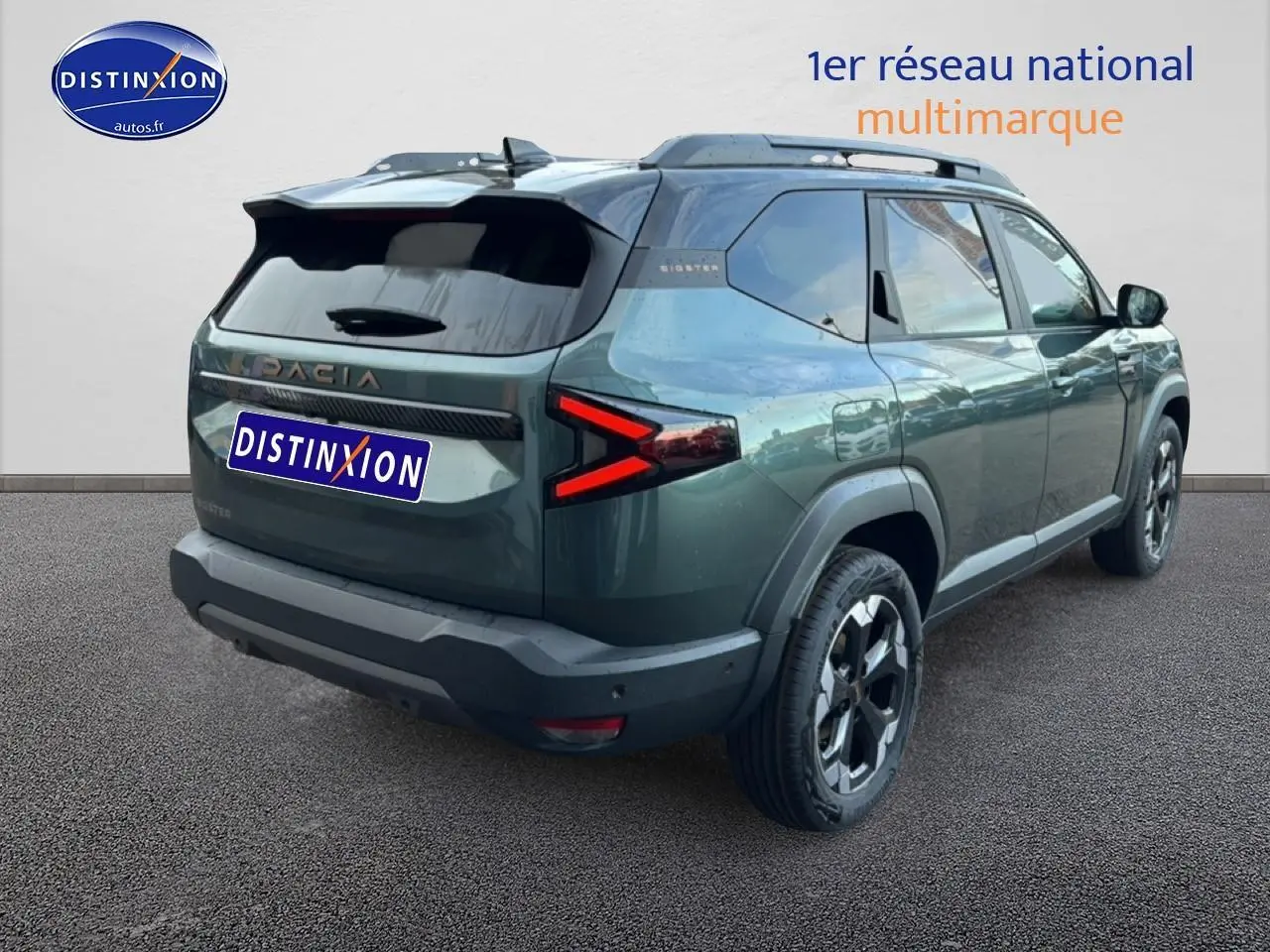 Vue 3/4 arrière droite du Dacia Bigster vert cèdre avec feux arrière LED en forme de flèche et barres de toit noires.