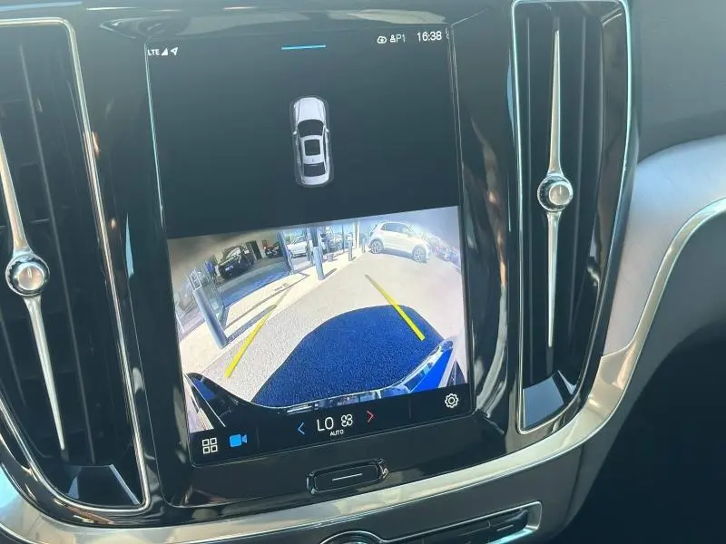 Écran tactile intérieur montrant la caméra de recul d'une Volvo S60 gris Platinium, avec guidage de trajectoire jaune.