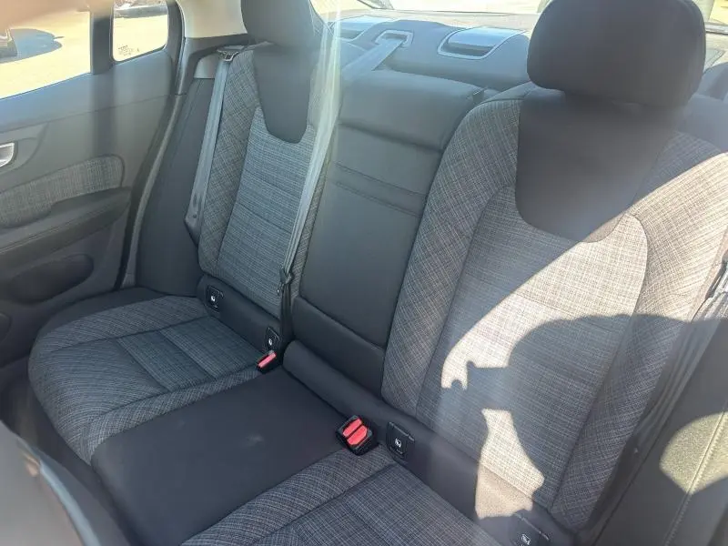 Vue intérieure sur la banquette arrière grise à motifs du Volvo S60 2024, avec ceintures de sécurité et appuie-têtes visibles.