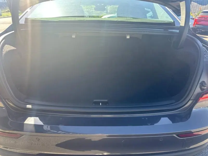 Coffre ouvert en vue arrière d'une Volvo S60 B4 gris Platinium métallisé sous lumière naturelle.