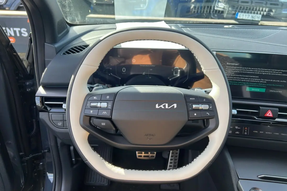 Vue rapprochée du volant cuir blanc et noir du Kia Sportage 2026 avec tableau de bord numérique et écran tactile.
