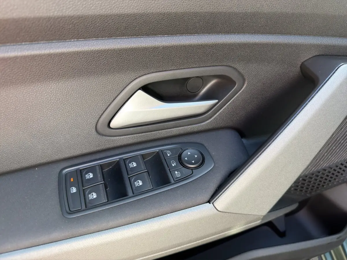 Gros plan sur la commande des vitres et poignée de porte intérieure côté conducteur d'une Dacia Bigster 2025 vert.