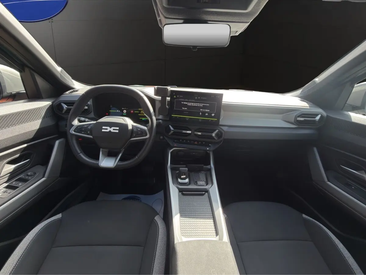 Vue intérieure avant du tableau de bord et volant noir du Dacia Bigster Journey Hybrid 2025 avec écran tactile central.
