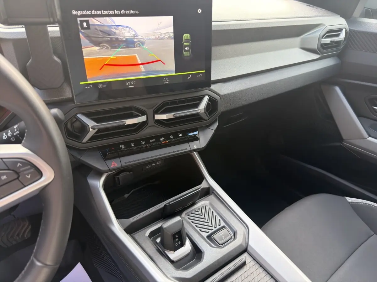 Vue intérieure du tableau de bord et console centrale du Dacia Bigster 2025, avec écran tactile et levier de boîte auto.