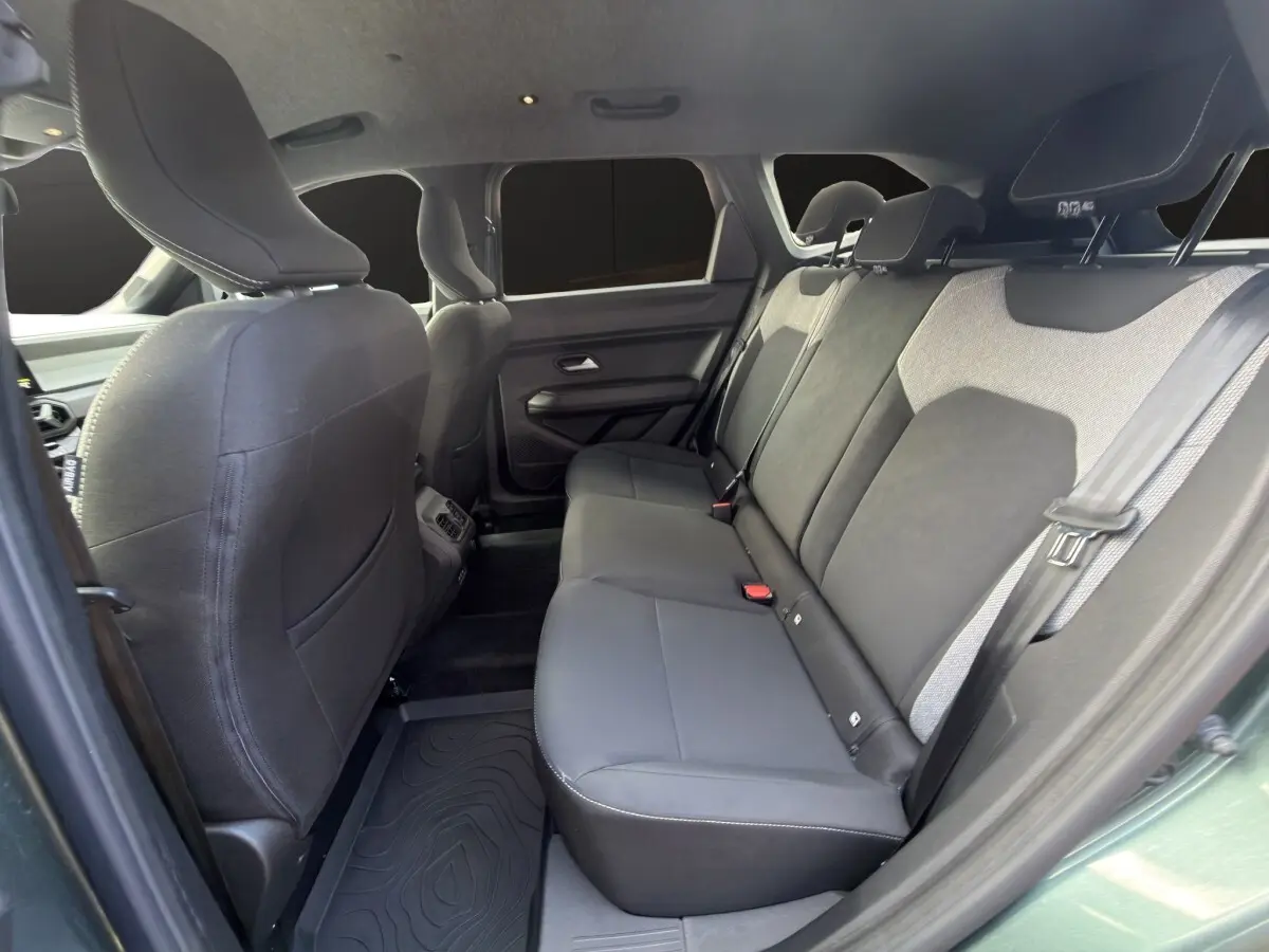 Vue intérieure côté gauche montrant la banquette arrière noire et grise du Dacia Bigster Journey Hybrid 2025 vert avec attelage.