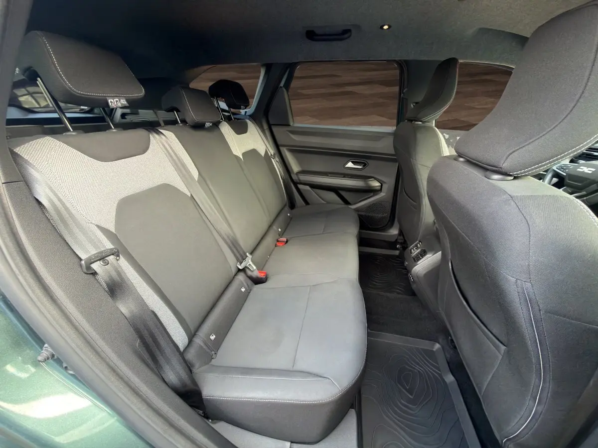 Vue intérieure côté droit sur la banquette arrière grise du Dacia Bigster Journey hybride vert avec attelage visible.