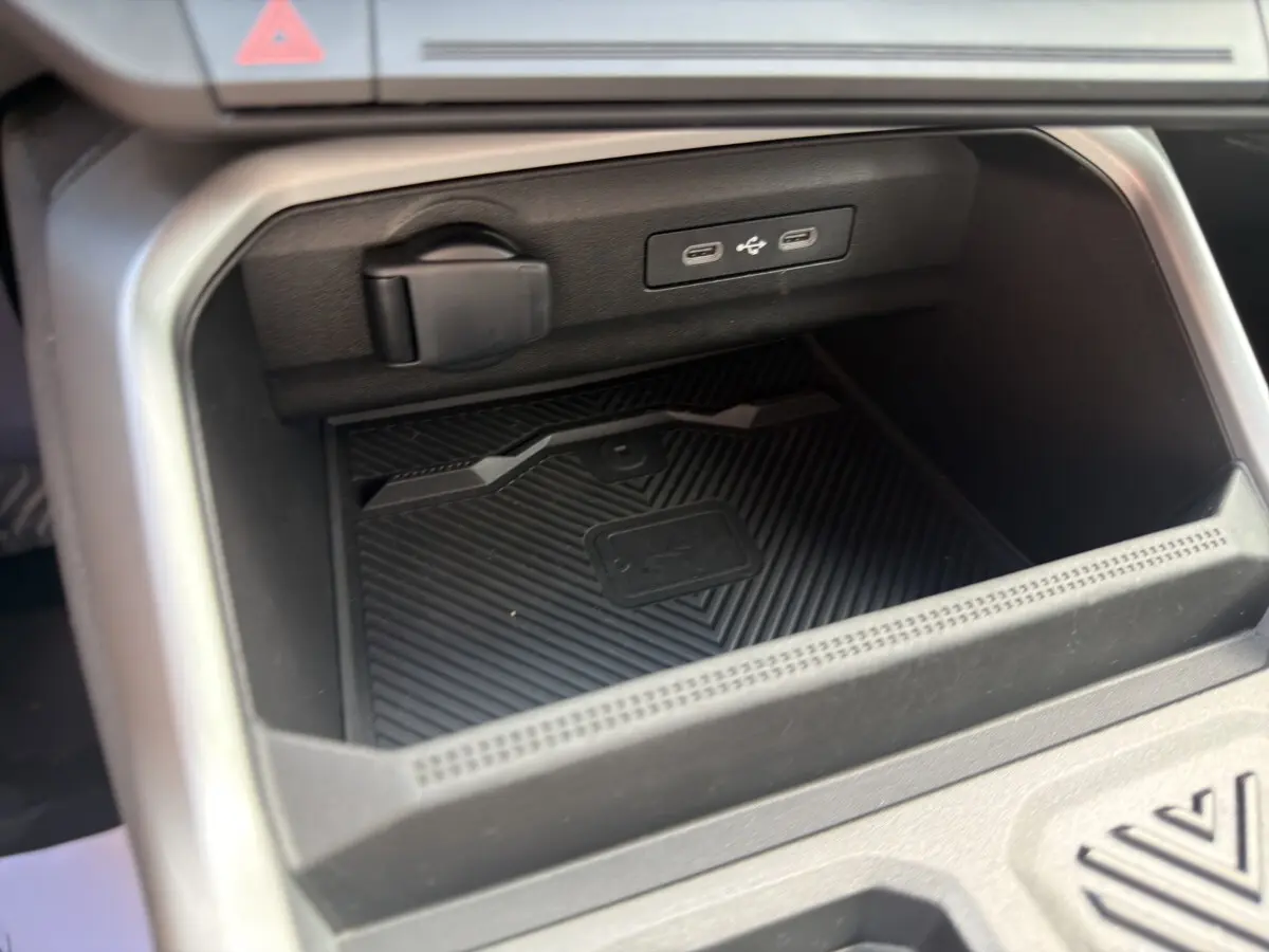 Gros plan sur la zone de recharge sans fil et ports USB dans l'habitacle noir du Dacia Bigster Journey hybride 2025.