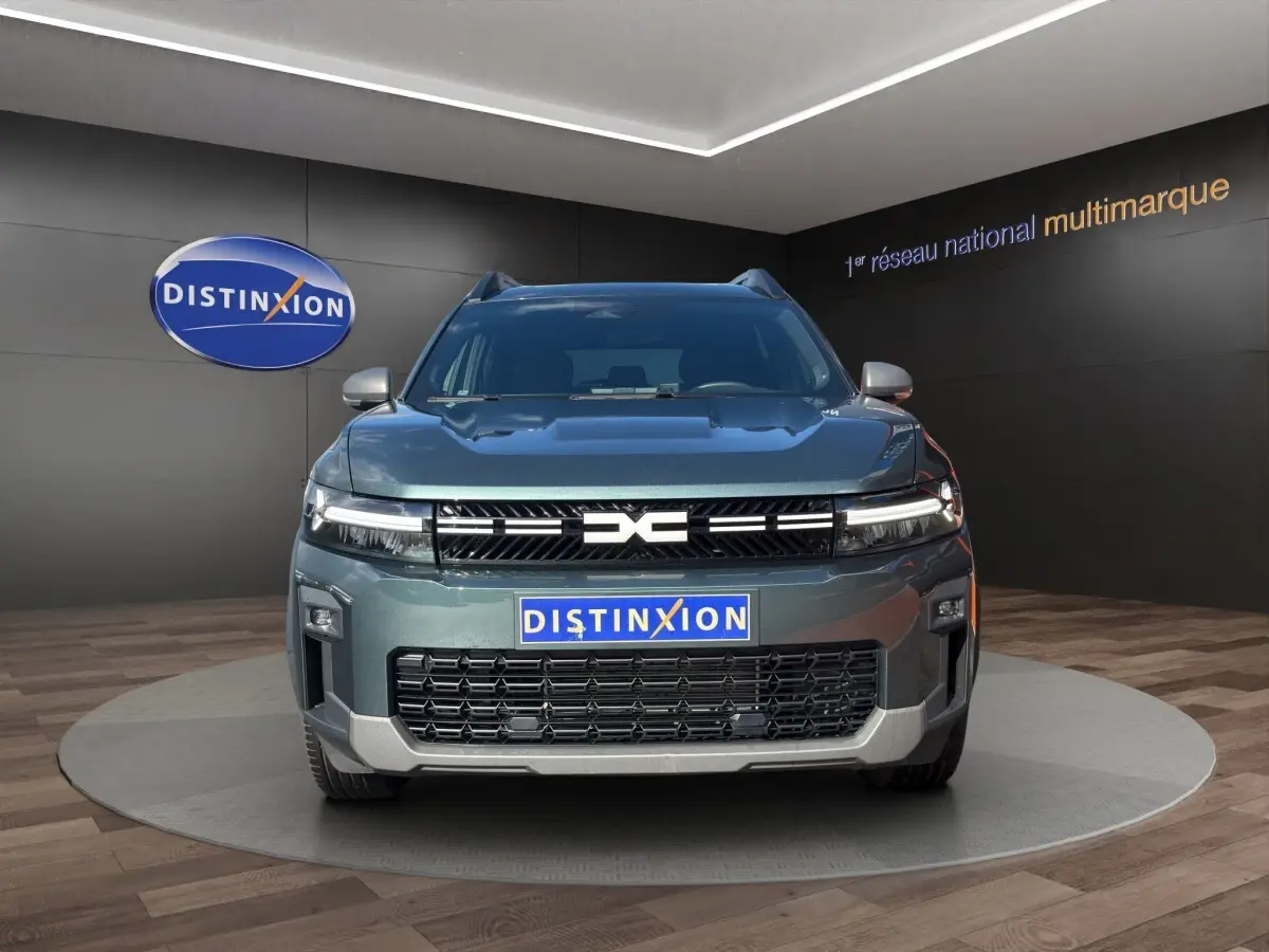 Vue avant du Dacia Bigster vert 2025 avec calandre noire et logo central distinctif, présenté en showroom.