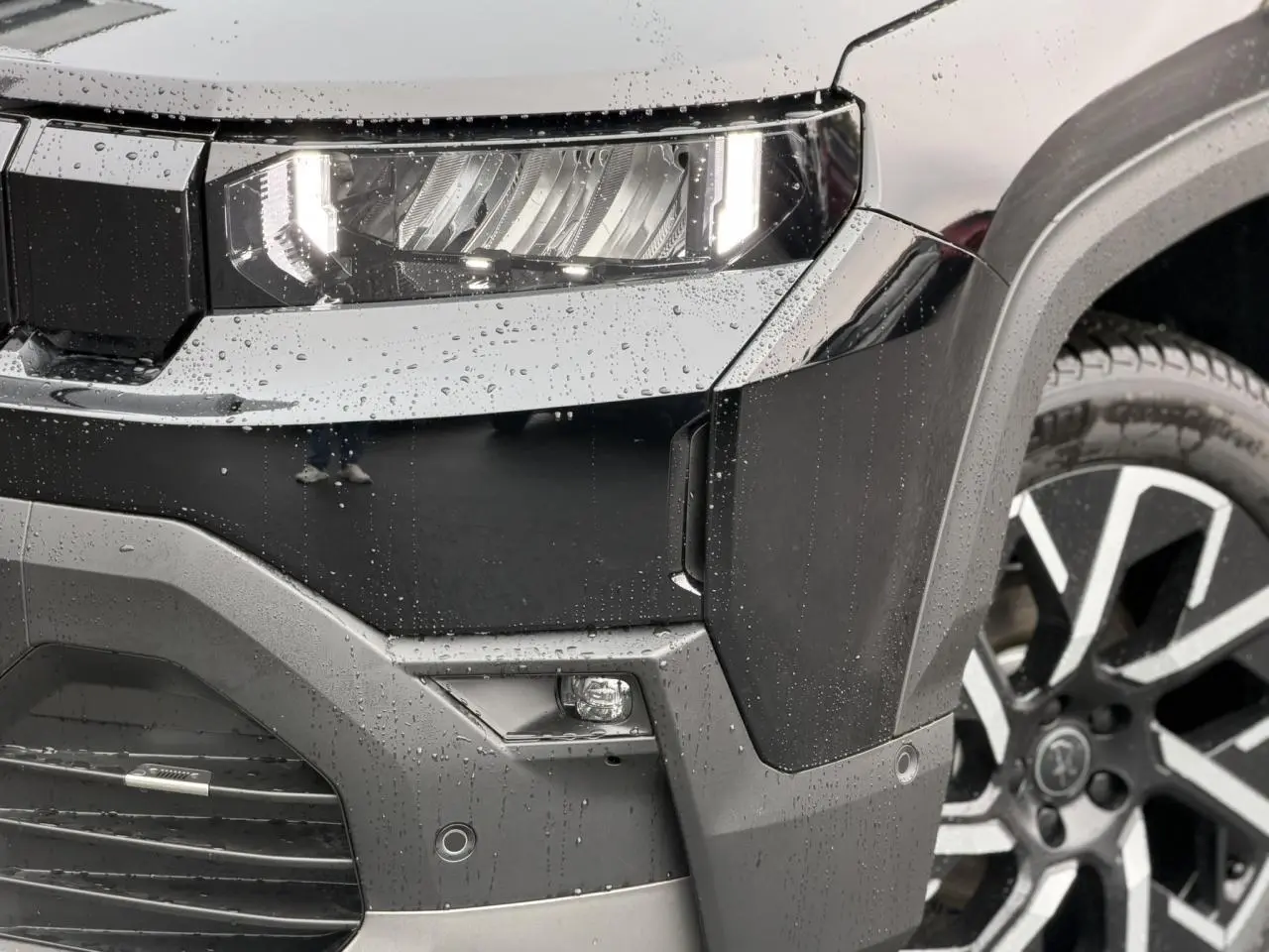 Gros plan sur l'avant droit noir Vulcano du Jeep Compass 2026, avec projecteur LED et jante alliage 19 pouces.