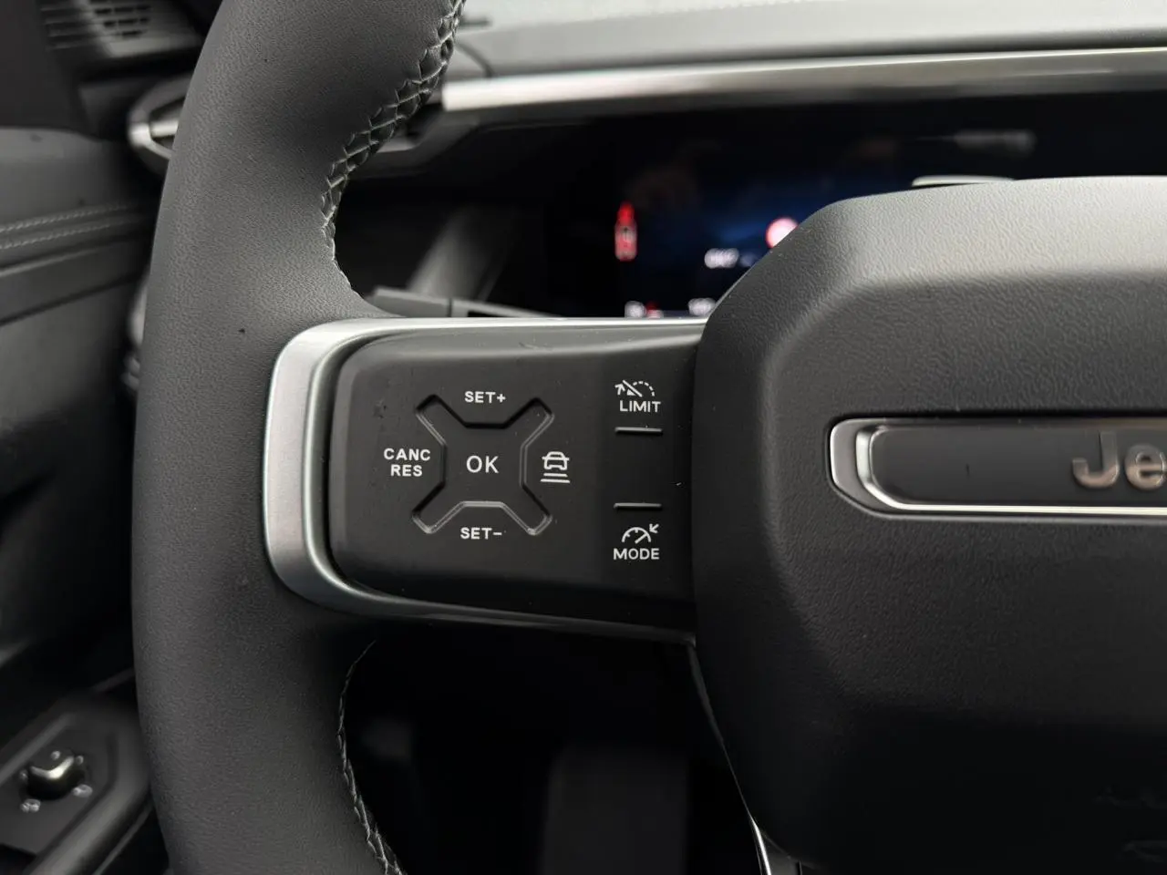 Gros plan sur le volant noir du Jeep Compass 2026 avec commandes intégrées et logo Jeep visible.