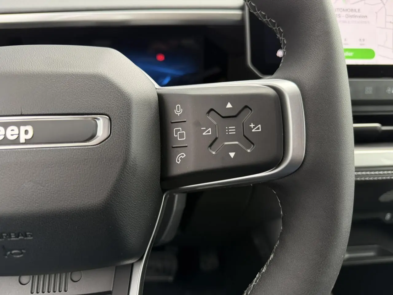Gros plan sur la partie droite du volant noir du Jeep Compass 2026, avec commandes multifonctions et écran tactile visible.