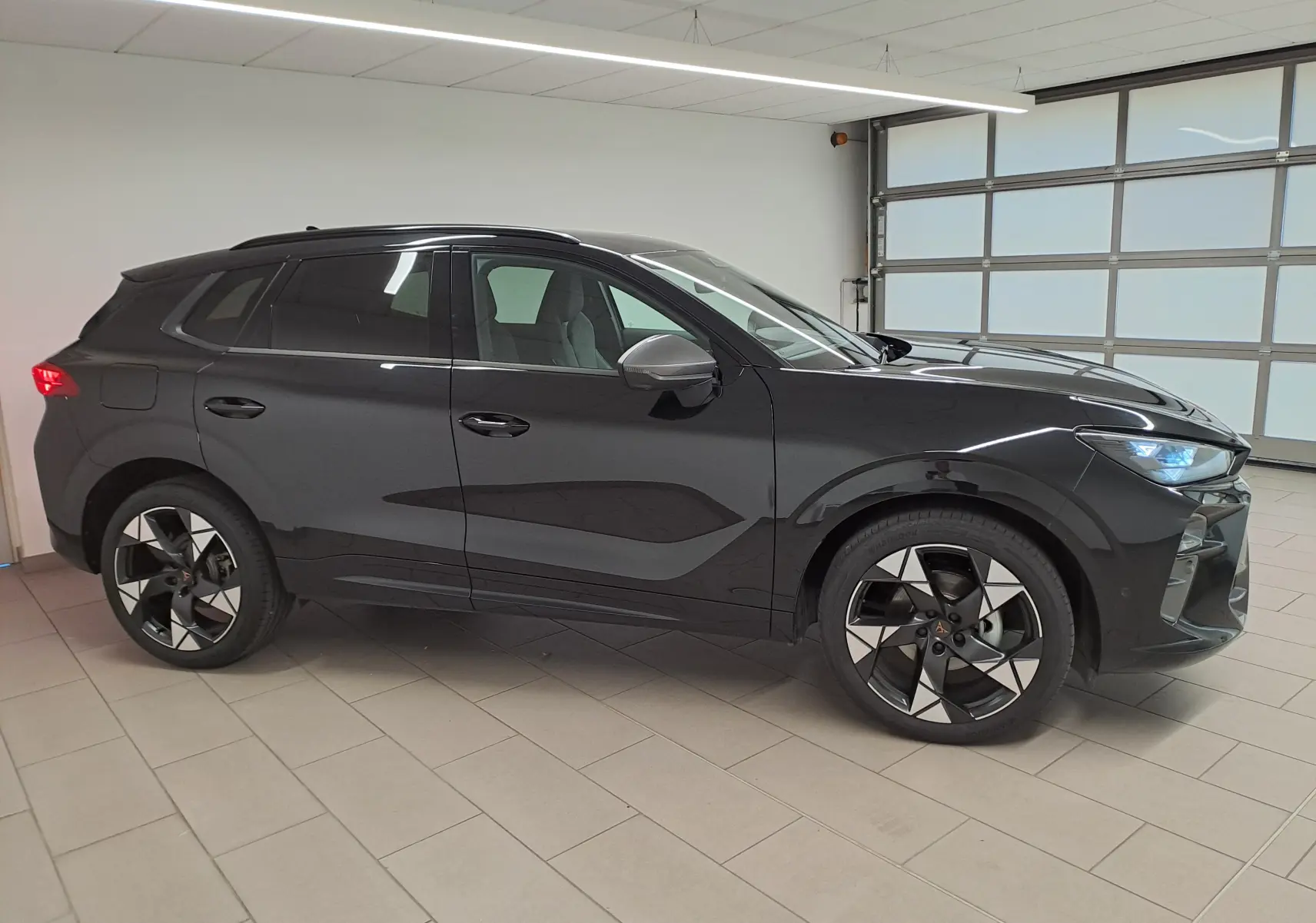 Vue de profil droit du CUPRA TERRAMAR 2025 noir minuit avec jantes 20'' Gravity usinées dans un intérieur lumineux.