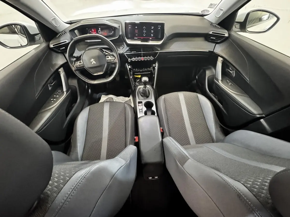 Vue intérieure avant du Peugeot 2008 blanc, montrant le volant cuir multifonctions et l’écran tactile central.